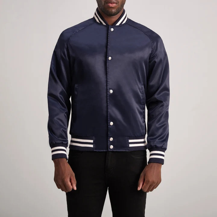 Navy blue varsity jacket with white accents worn by a person on a plain background
