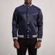 Navy blue varsity jacket with white accents worn by a person on a plain background
