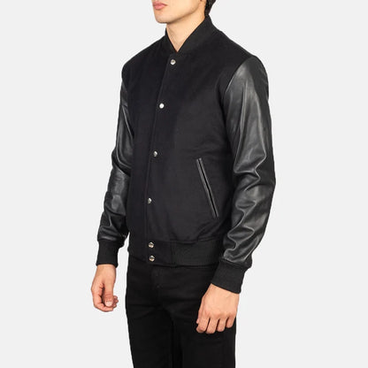 Black varsity jacket with leather sleeves worn by a person on a white background