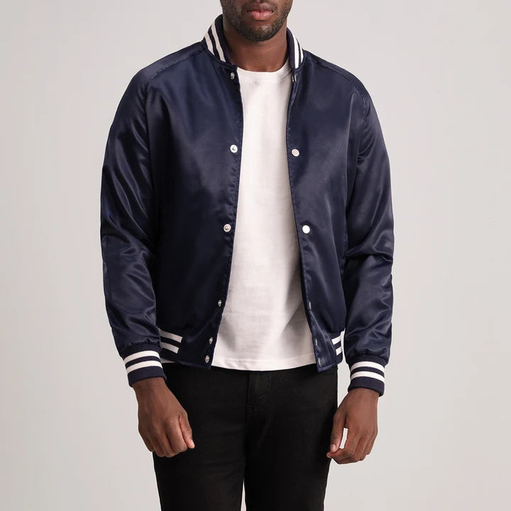 Man wearing a navy blue varsity jacket with white accents on a plain background