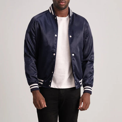Man wearing a navy blue varsity jacket with white accents on a plain background
