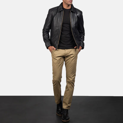 Man wearing a black leather jacket, black shirt, beige pants, and black shoes on a gradient background.