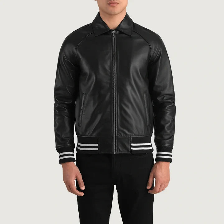 A man wearing a black leather bomber jacket with white striped ribbed cuffs and hem, paired with black pants, against a light gray background.