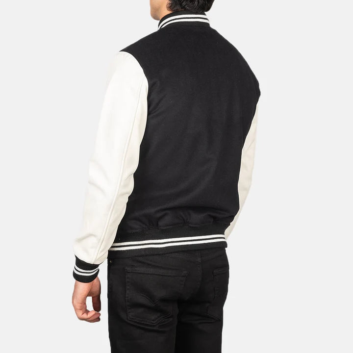 Person wearing a black and white varsity jacket on a plain background