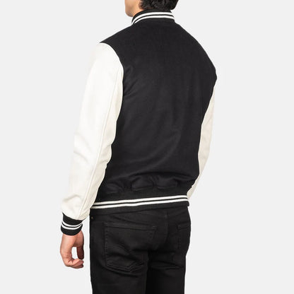 Person wearing a black and white varsity jacket on a plain background