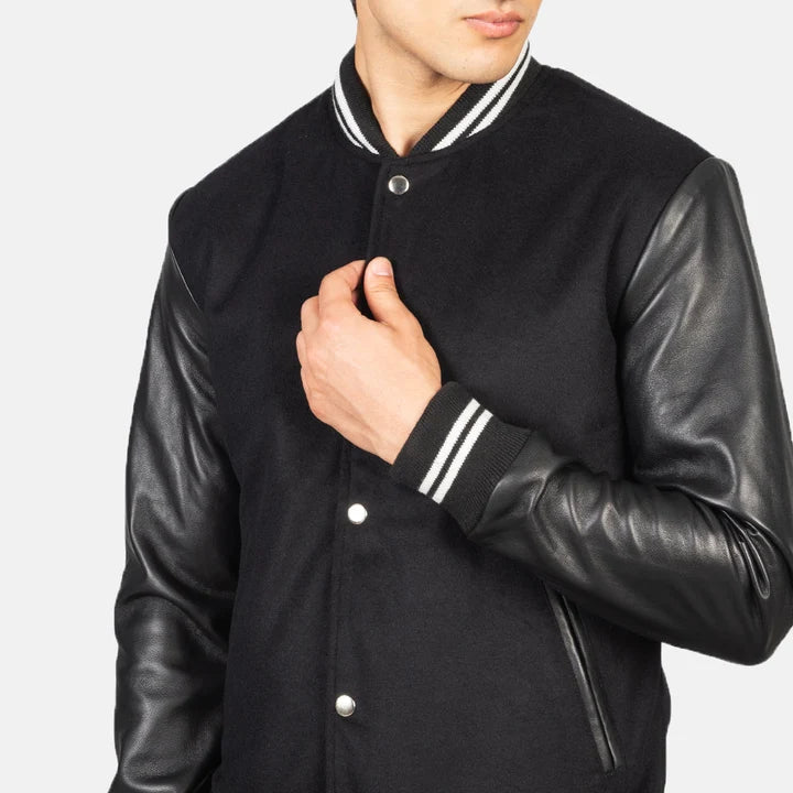 Black varsity jacket with leather sleeves on a plain background